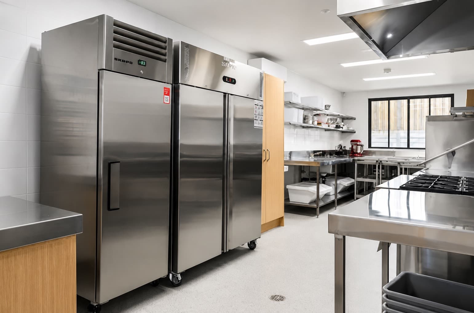 Commercial kitchen with a seamless speckled floor coating around a drain and stainless steel equipment